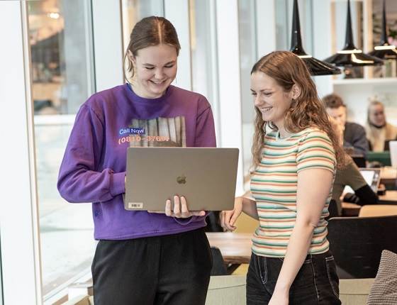 studerende står ved en computer og griner